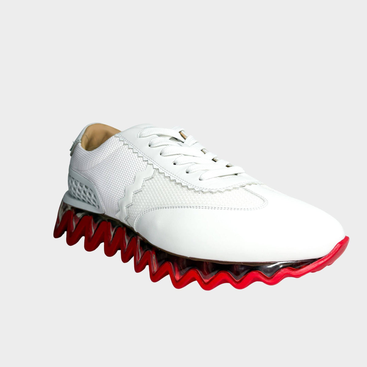Side profile view of a Christian Louboutin Loubishark sneaker in white leather, highlighting the signature red and white serrated shark-tooth sole.