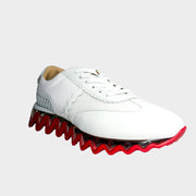 Side profile view of a Christian Louboutin Loubishark sneaker in white leather, highlighting the signature red and white serrated shark-tooth sole.