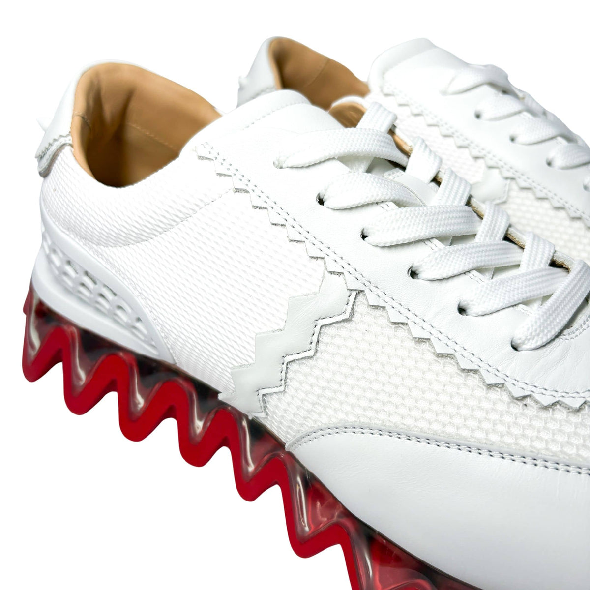 Close-up side profile of the white Christian Louboutin Loubishark flat sneaker, focusing on the textured leather upper and wavy midsole trim.