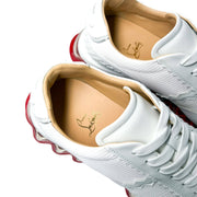 Angled top-down studio shot of a pair of Christian Louboutin Loubishark white sneakers, highlighting the premium tan leather lining.