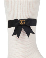 Detailed close-up view of white Gucci cotton sock showcasing the black grosgrain ribbon bow and gold thread GG logo embellishment.