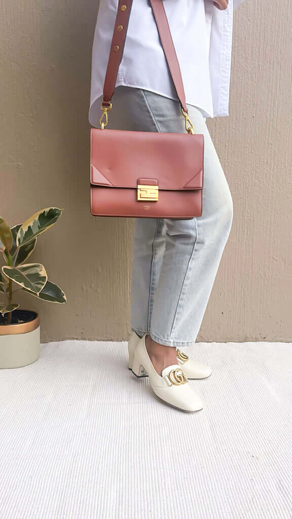 Side profile view of a model wearing the brown Fendi Kan U bag, showcasing its size, hang, and adjustable shoulder strap.