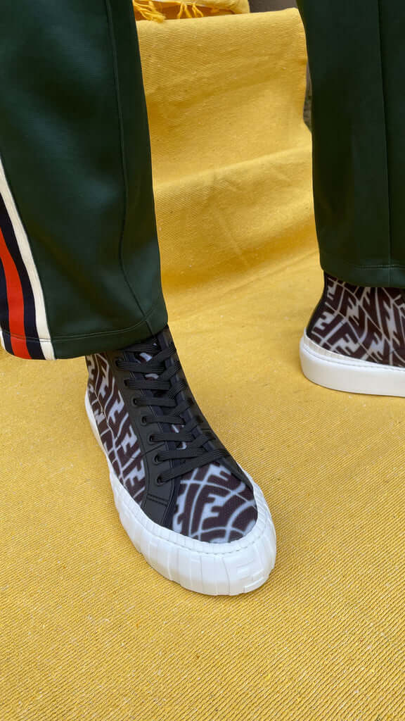 Model wearing black Fendi FF Vertigo high-top mesh trainers styled with black side-stripe trousers.