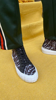 Model wearing black Fendi FF Vertigo high-top mesh trainers styled with black side-stripe trousers.
