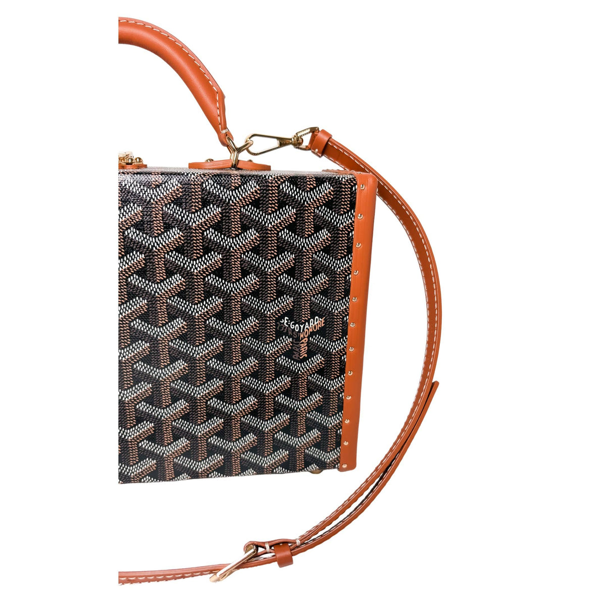 Three-quarter view of Goyard Grand Hôtel Trunk Bag detailing tan leather edge binding and strap attachment.