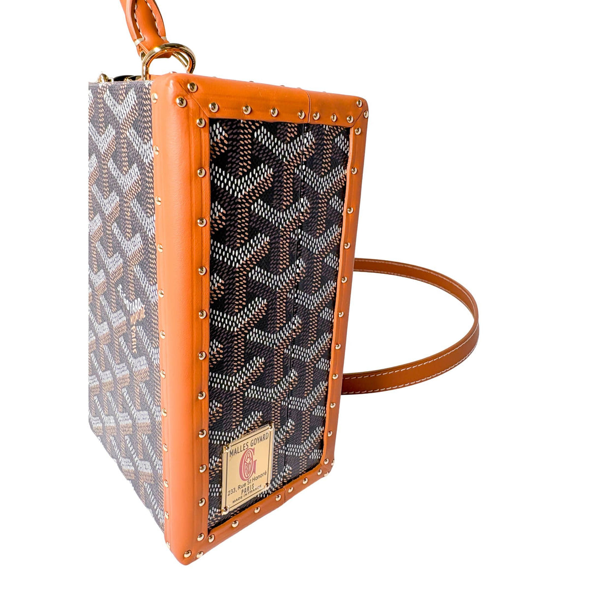 Side detail view of Goyard Grand Hôtel Trunk Bag highlighting the polished metal clasp and leather strap attachment.