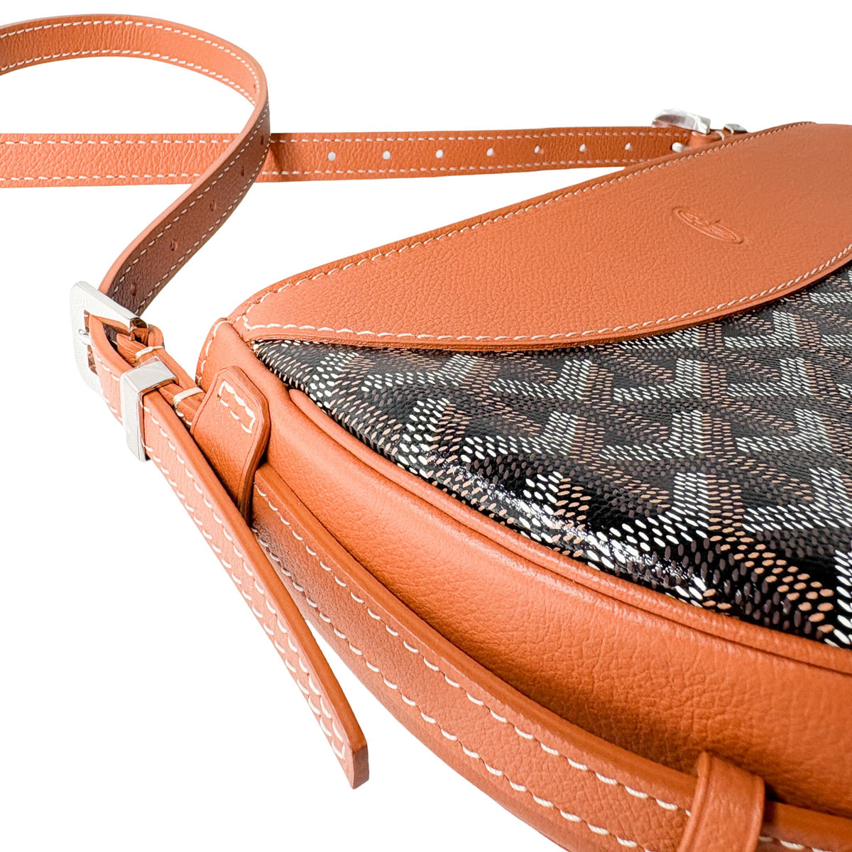 Three-quarter view of Goyard Hirondelle bag showing curved tan leather top detail and chevron canvas pattern.