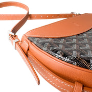 Three-quarter view of Goyard Hirondelle bag showing curved tan leather top detail and chevron canvas pattern.