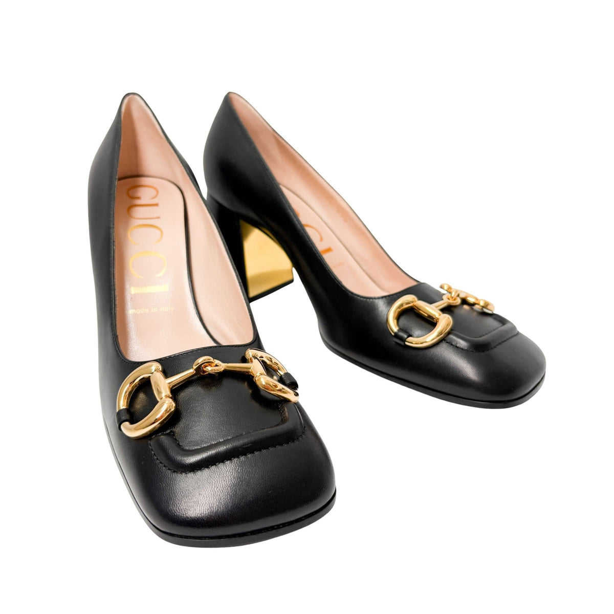 Three-quarter studio shot of a pair of black leather Gucci Baby Pumps, highlighting the classic square toe box and gold-toned horsebit buckle details.