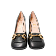 Symmetrical front view of a pair of Gucci Baby Pumps side-by-side, emphasizing the elegant square toe shape and branded gold buckles.