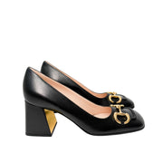 Side perspective of the black Gucci Baby Pumps arranged in a staggered layout, showcasing the sleek lines of the leather upper.