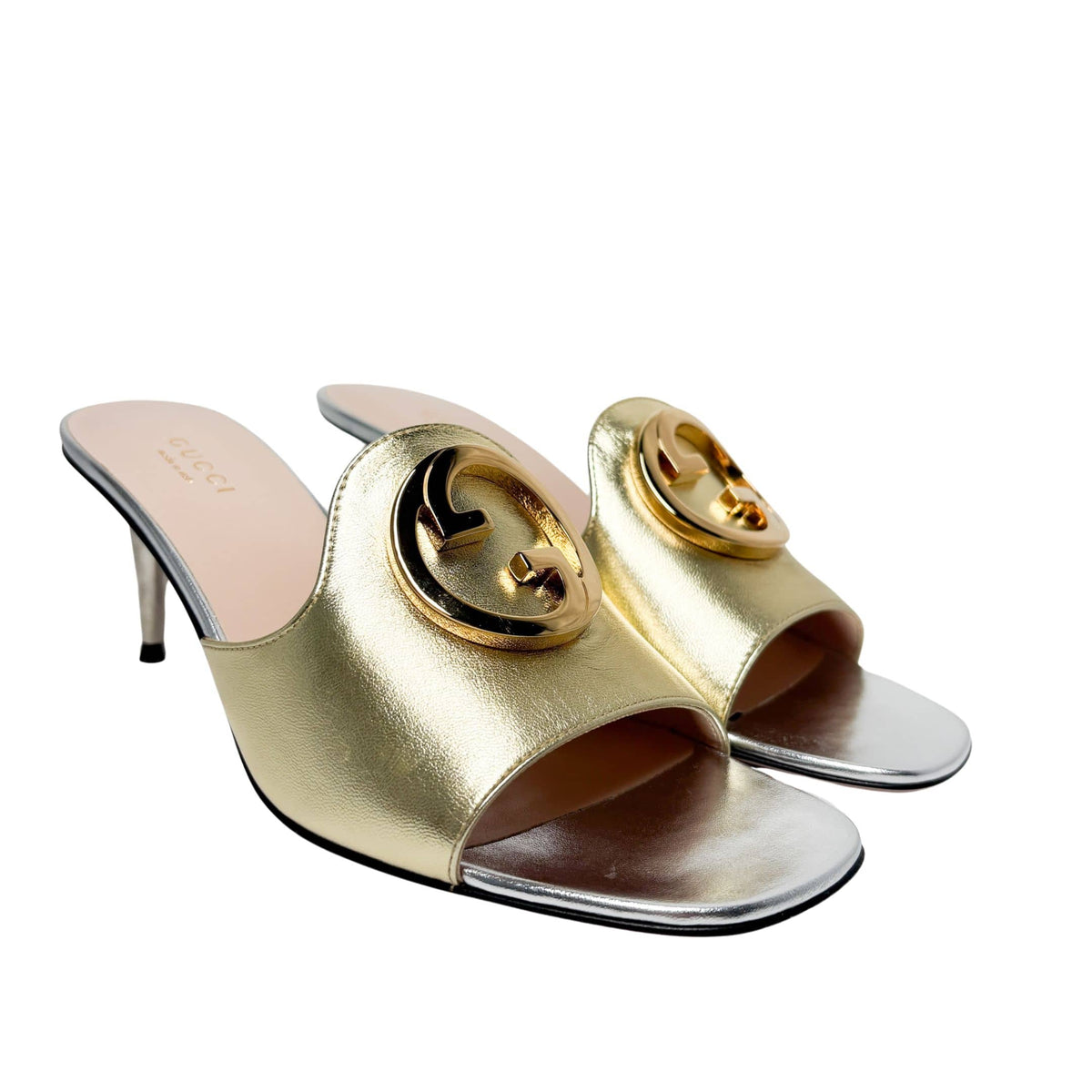 Three-quarter studio profile of the gold and silver Gucci Blondie high heel mules, showcasing the elegant curve of the open-toe design.