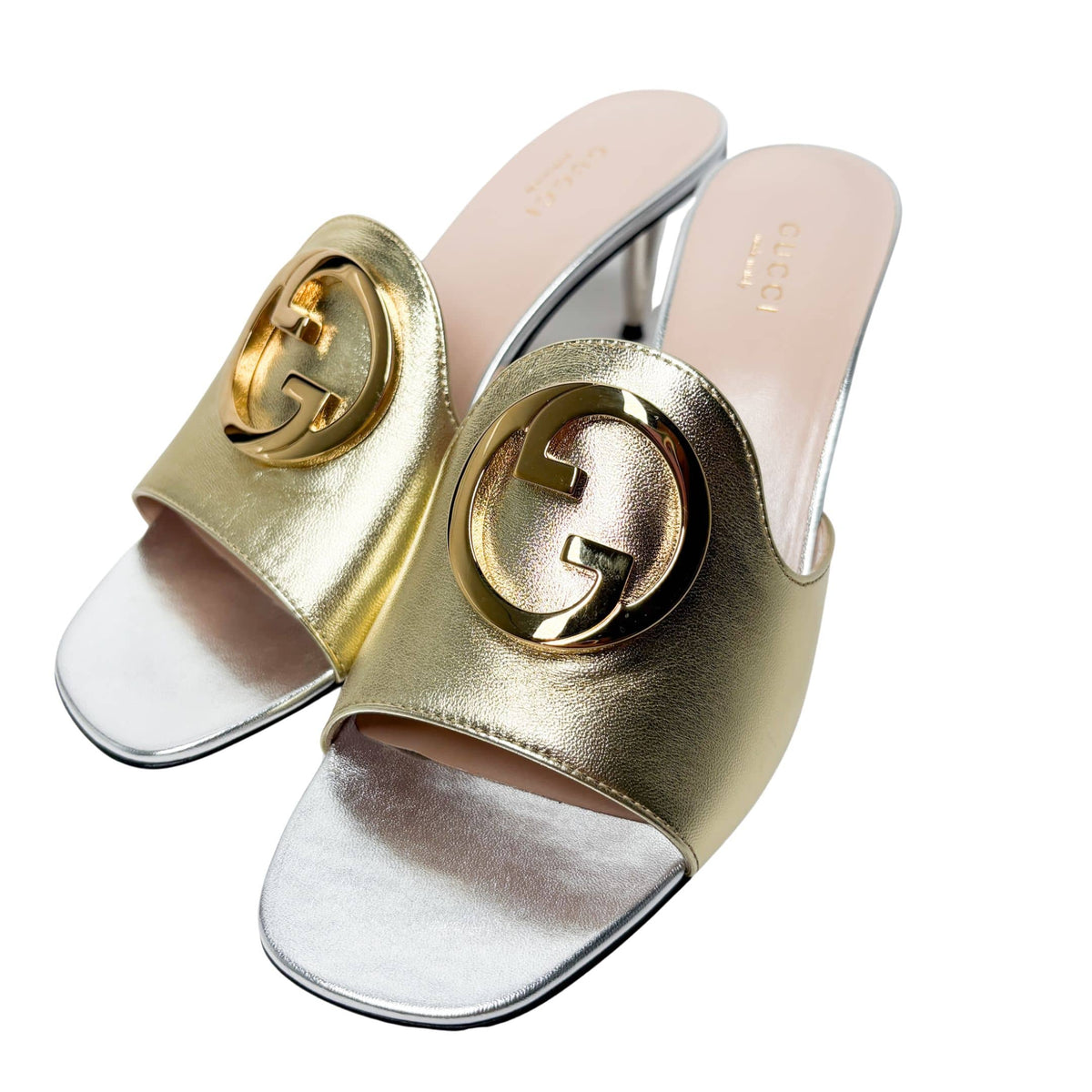 Overhead angled studio shot of a pair of metallic gold Gucci Blondie sandals, displaying the light cream leather insoles with subtle Gucci branding.