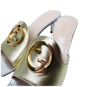 Close-up three-quarter view of the Gucci Blondie gold leather sandals, showcasing the detailed stitching and reflection on the metallic finish.