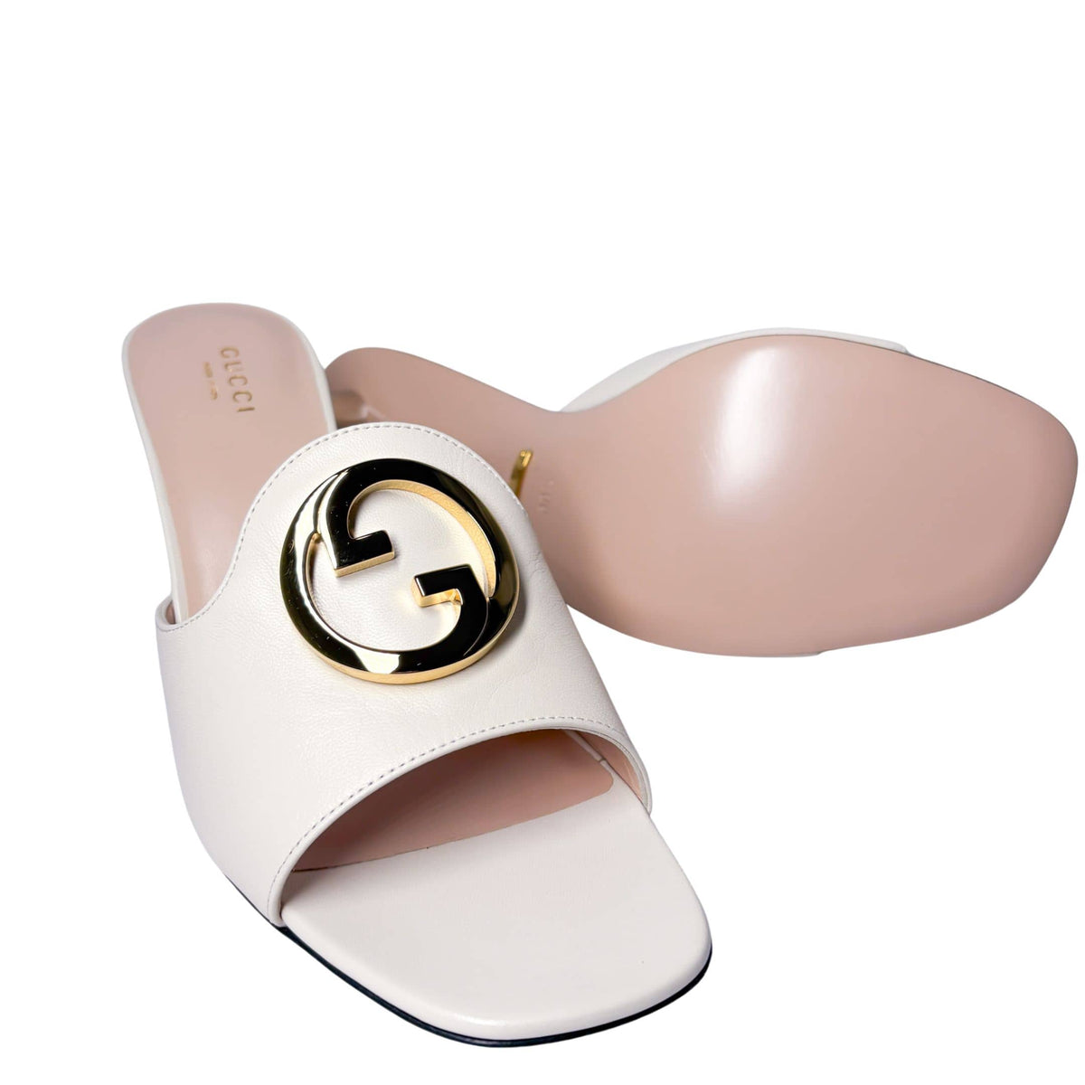 Detailed side perspective shot focusing on the bold circular gold interlocking G hardware on the strap of the white Gucci Blondie mule.