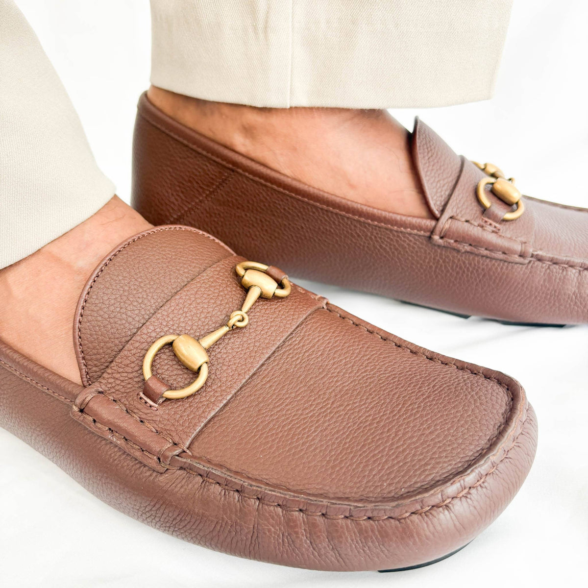 Three-quarter angle view of Gucci brown leather men's horsebit slip-on shoe highlighting horsebit hardware.