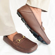 On-foot dynamic view of Gucci brown leather Horsebit loafers styled with light beige trousers.