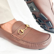 Close-up view of gold-tone horsebit detail on Gucci brown leather driver loafers.