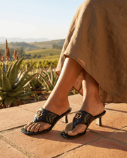 On-foot outdoor view of the black leather Gucci Charlotte thong sandals, captured during sunset to showcase a casual luxury style.
