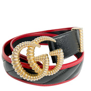 Side angle view of the coiled black Gucci leather belt, highlighting the red piping edge detail and aged gold GG metal buckle.