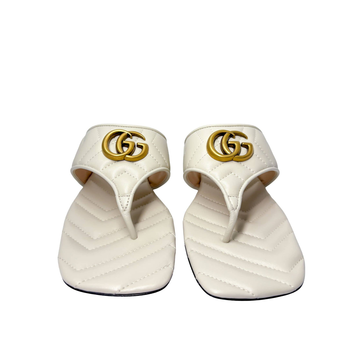 Symmetrical front-facing studio view of a pair of white Gucci Marmont Charlotte sandals side-by-side, showcasing the open toe design.