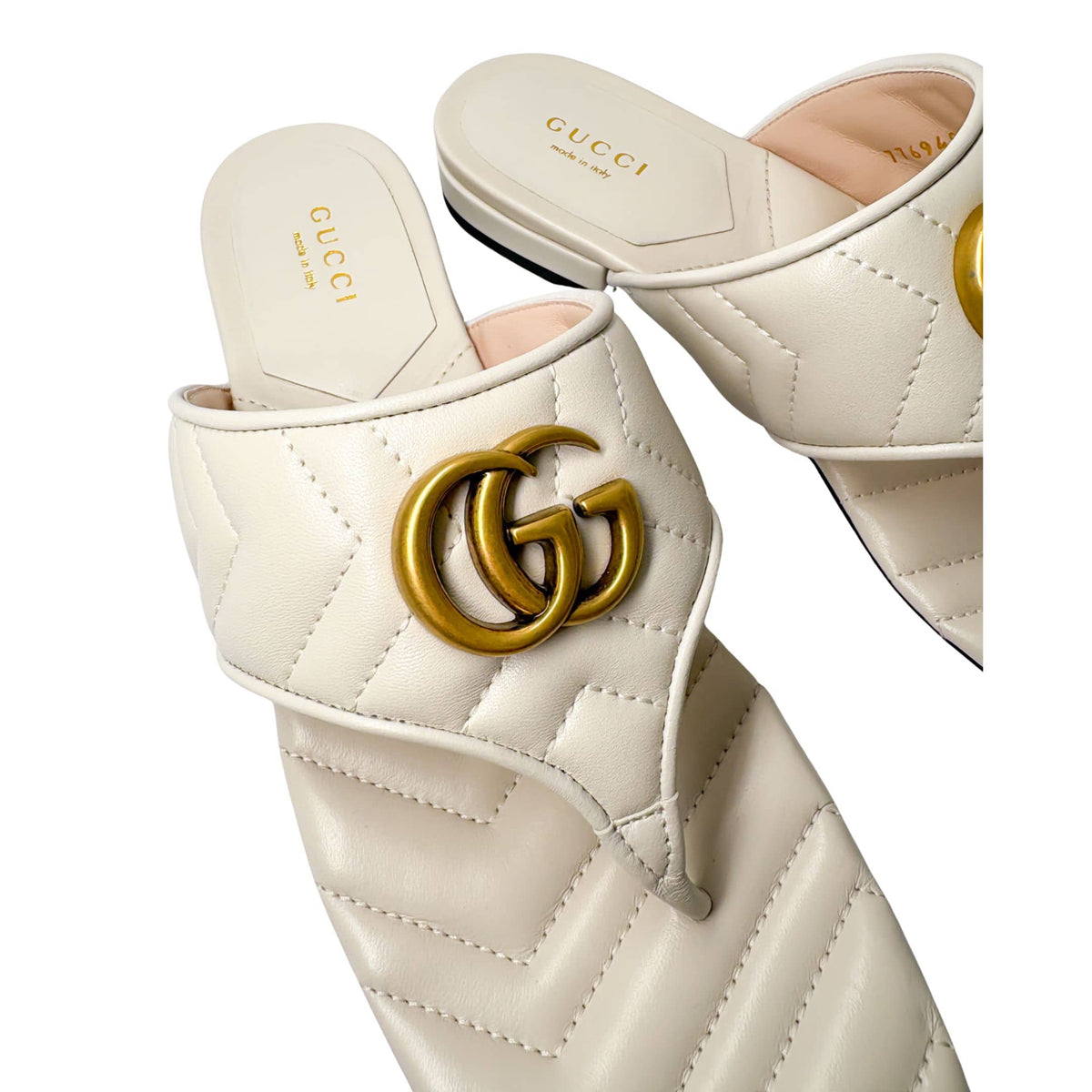 Close-up three-quarter view of the white Gucci Charlotte leather sandal, highlighting the quilted chevron pattern and flat sole profile.