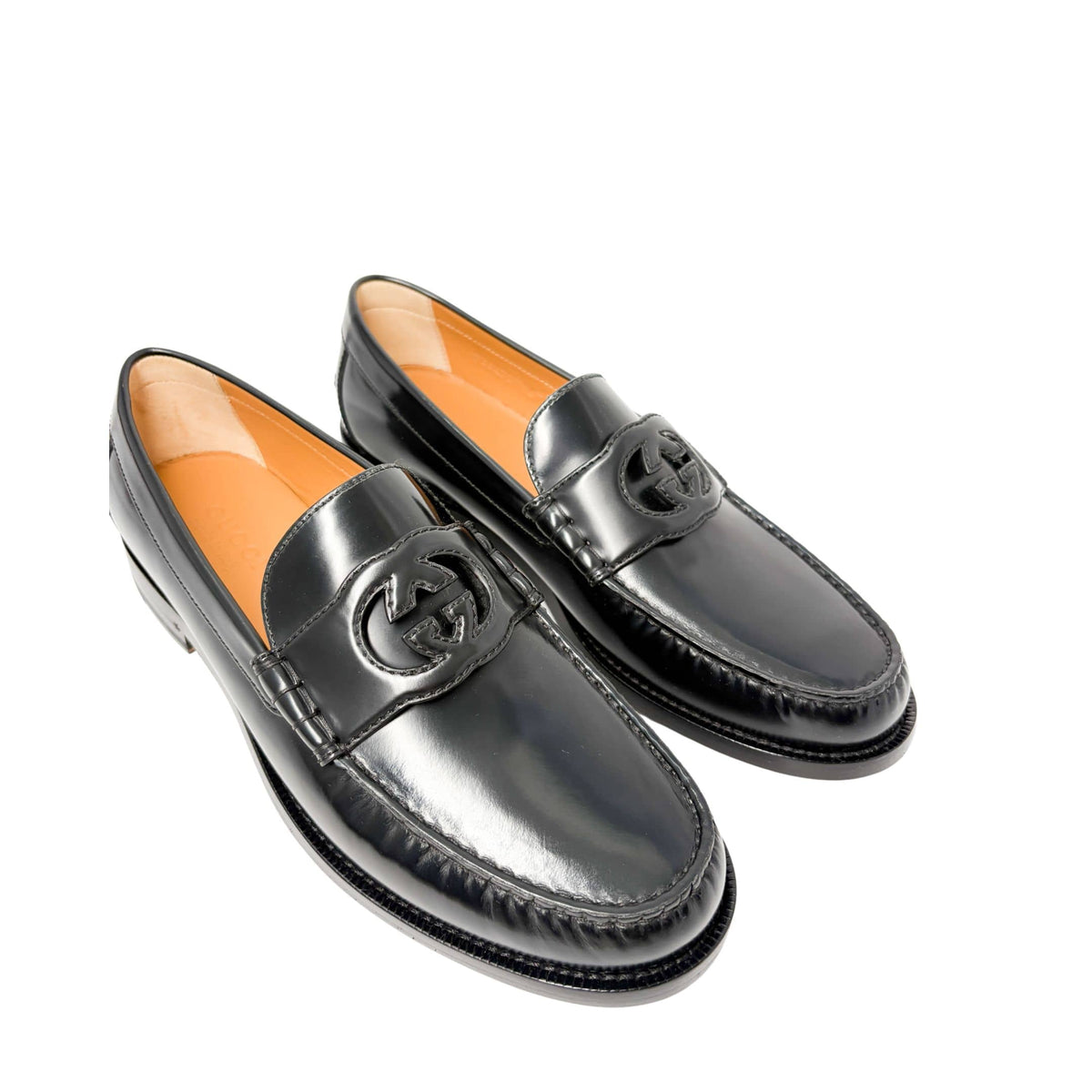 Three-quarter view of a pair of Gucci Millennial Ribot black leather loafers displaying the sleek slip-on silhouette.