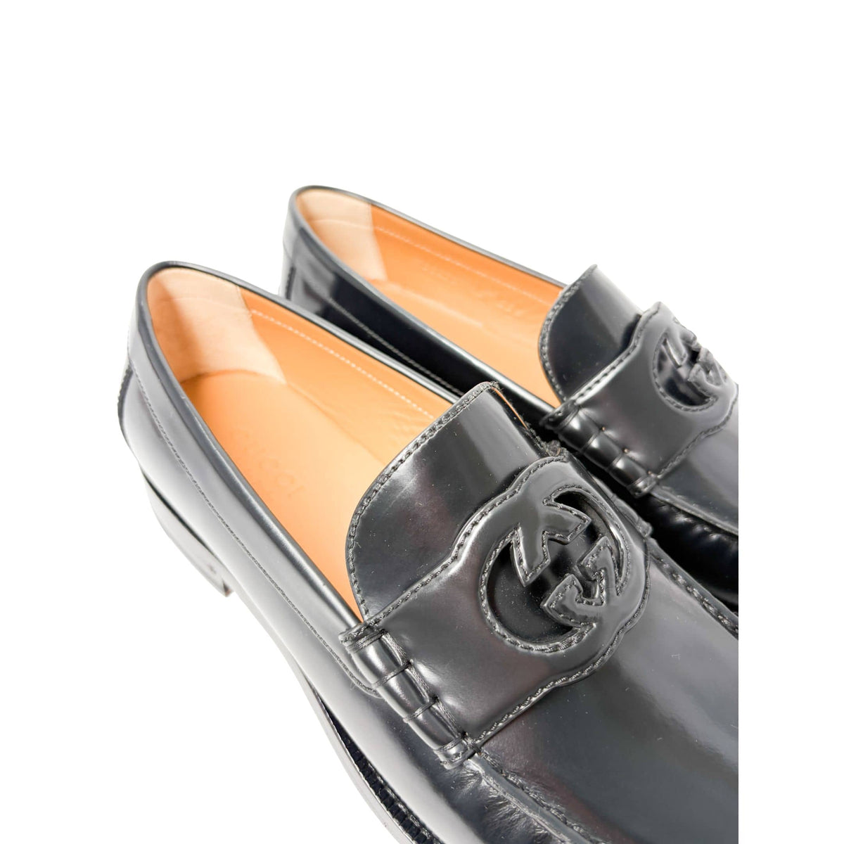 Detailed macro view of Gucci Millennial Ribot black leather loafers focusing on toe box stitching and signature motif embellishment.