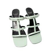 Symmetrical front-facing studio view of a pair of Pacific Green Gucci Regent heeled sandals side-by-side, emphasizing the open toe box.