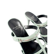 Three-quarter rear perspective of the green Gucci Regent sandals, highlighting the slender stiletto high heel and polished leather footbed.