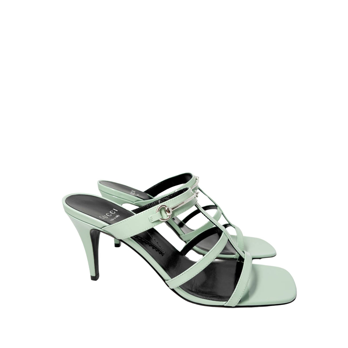 Staggered side view of both Gucci Regent green leather sandals, showcasing the elegant curve of the ankle straps and silhouette.