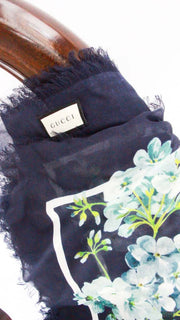 Close-up side view of the folded navy blue Gucci Bloom silk scarf, highlighting the intricate floral print pattern and luxurious silk texture.