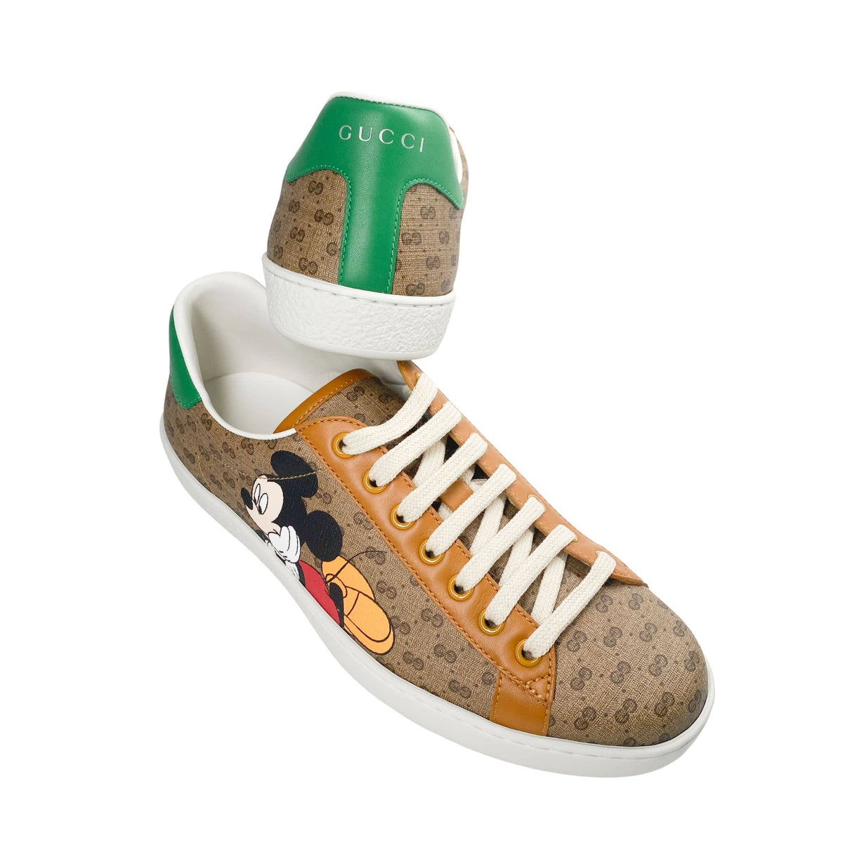 Angled profile view of Gucci x Disney Ace sneaker displaying white treaded outsole and brown GG canvas upper.