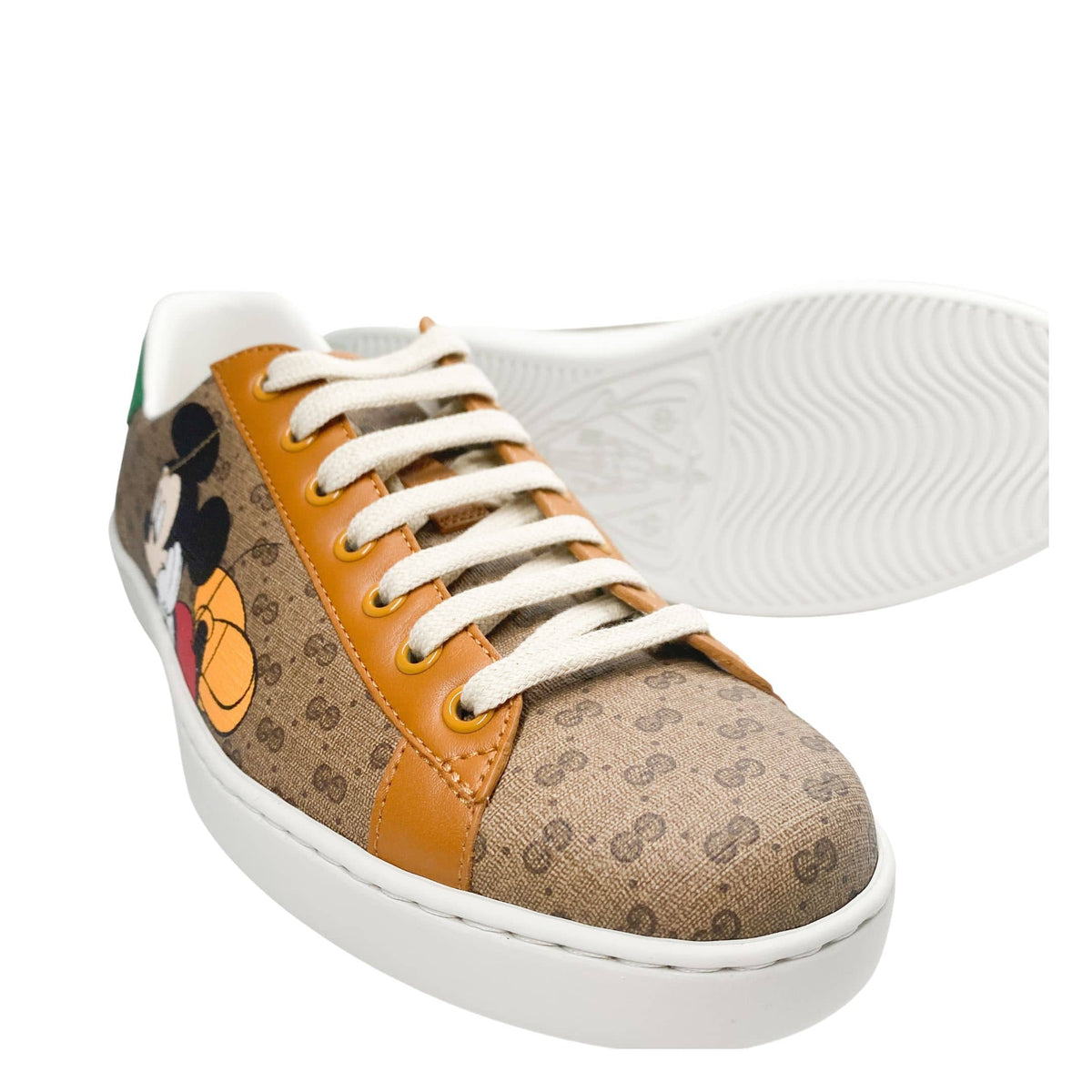 Close-up view of printed Mickey Mouse graphic and GG monogram canvas on Gucci Ace sneakers.