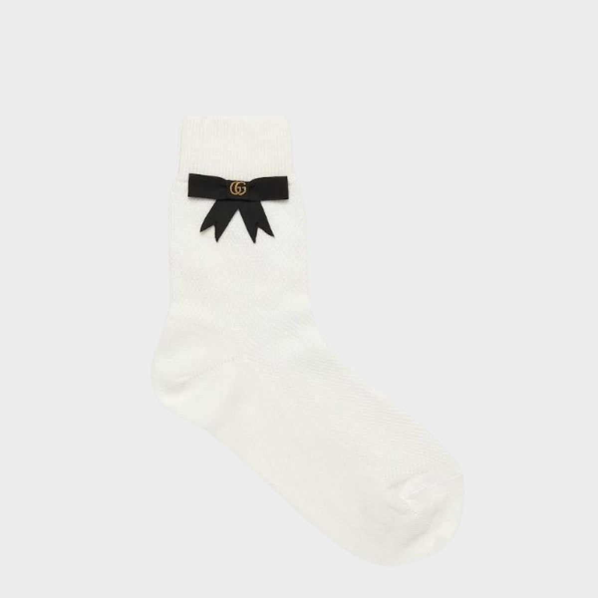 Pair of white Gucci stretch cotton socks featuring a black grosgrain ribbon bow and embroidered gold GG logo.
