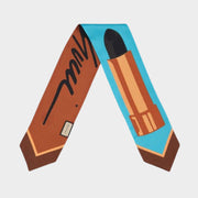 Gucci silk twilly scarf featuring a playful lipstick print with cursive logo script on a blue and orange border.