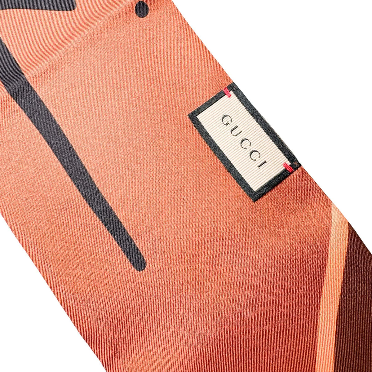 Close-up view of the Gucci silk scarf showcasing the woven brand label, hand-stitched borders, and smooth silk texture.