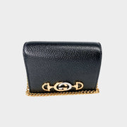 Front view of the Gucci Zumi card case wallet in black grainy leather, featuring mixed gold and silver Interlocking G Horsebit hardware and chain strap.