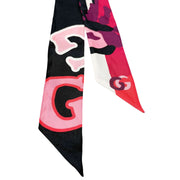Detailed view of the Gucci silk twilly ribbon highlighting the bold interlocking GG pattern and floral motif accents.