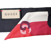 Close-up view of the Gucci silk twilly scarf displaying the official brand woven label alongside signature Gucci packaging.