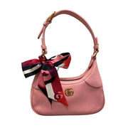 Gucci floral silk twilly scarf tied in an elegant bow around the handle of a pink leather shoulder bag.