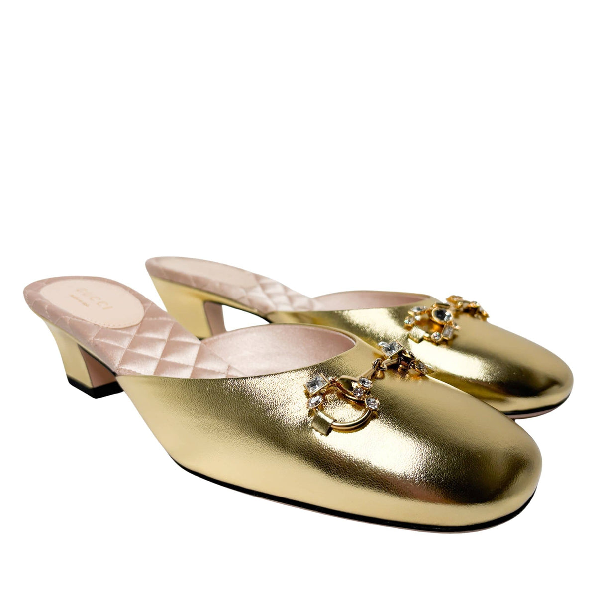 Staggered front-facing view of the gold Gucci Horsebit mules, emphasizing the radiant metallic finish and luxury evening style.