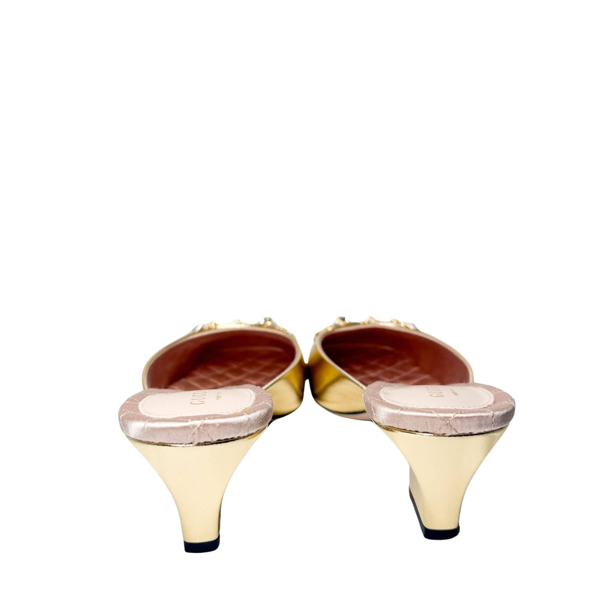 Rear view of the metallic gold Gucci mules from behind, showcasing the shape of the low block heels and clean construction.