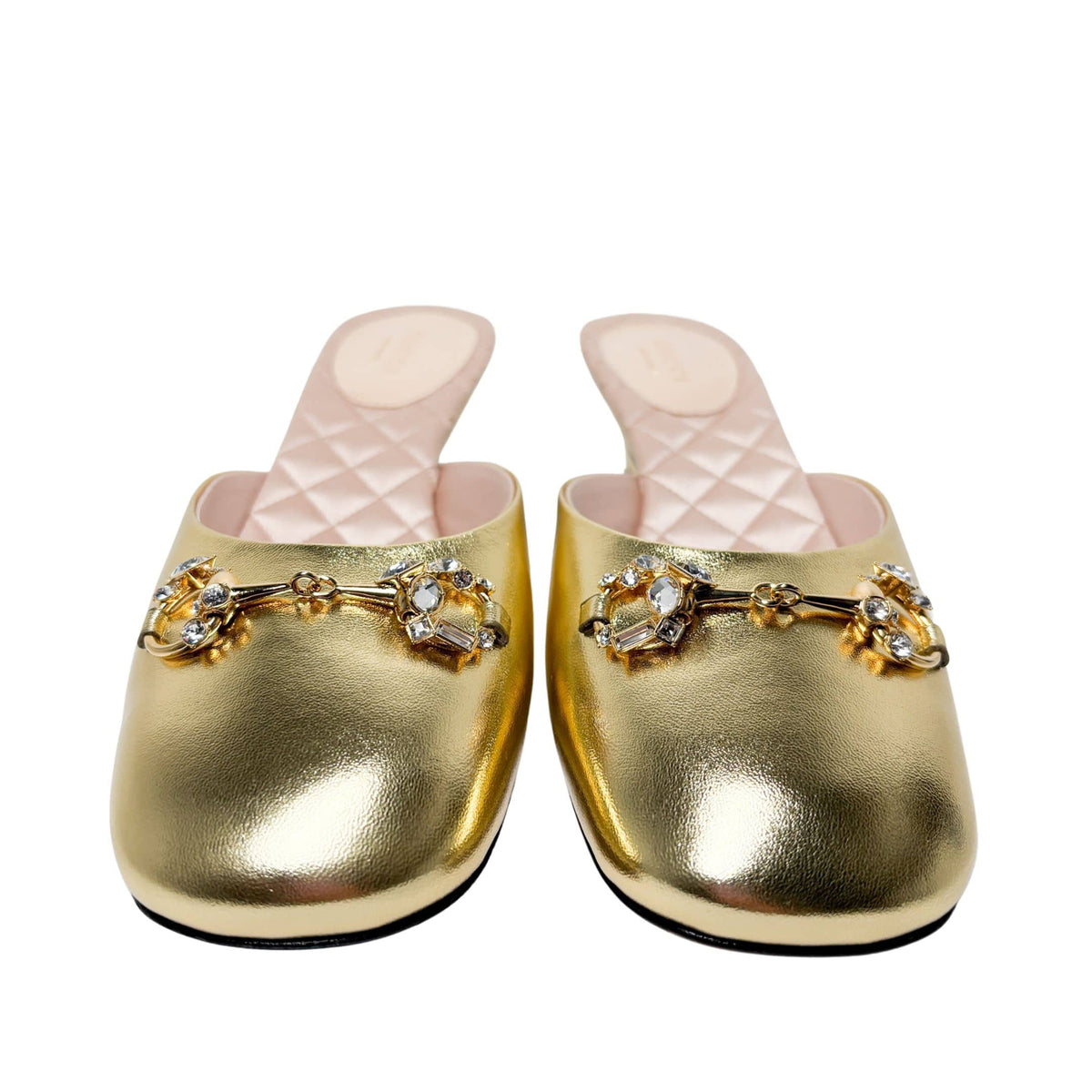 Symmetrical front view of the pair of gold Gucci Diamond Horsebit mules placed side-by-side against a neutral background.