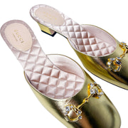 Top-down angled view of the gold Gucci mules, displaying the soft pink quilted leather insoles and debossed Gucci logo branding.