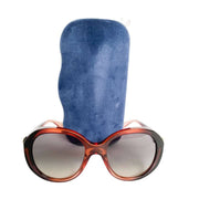 Frontal view of the oversized Gucci Bee round sunglasses presented on a blue velvet display holder.