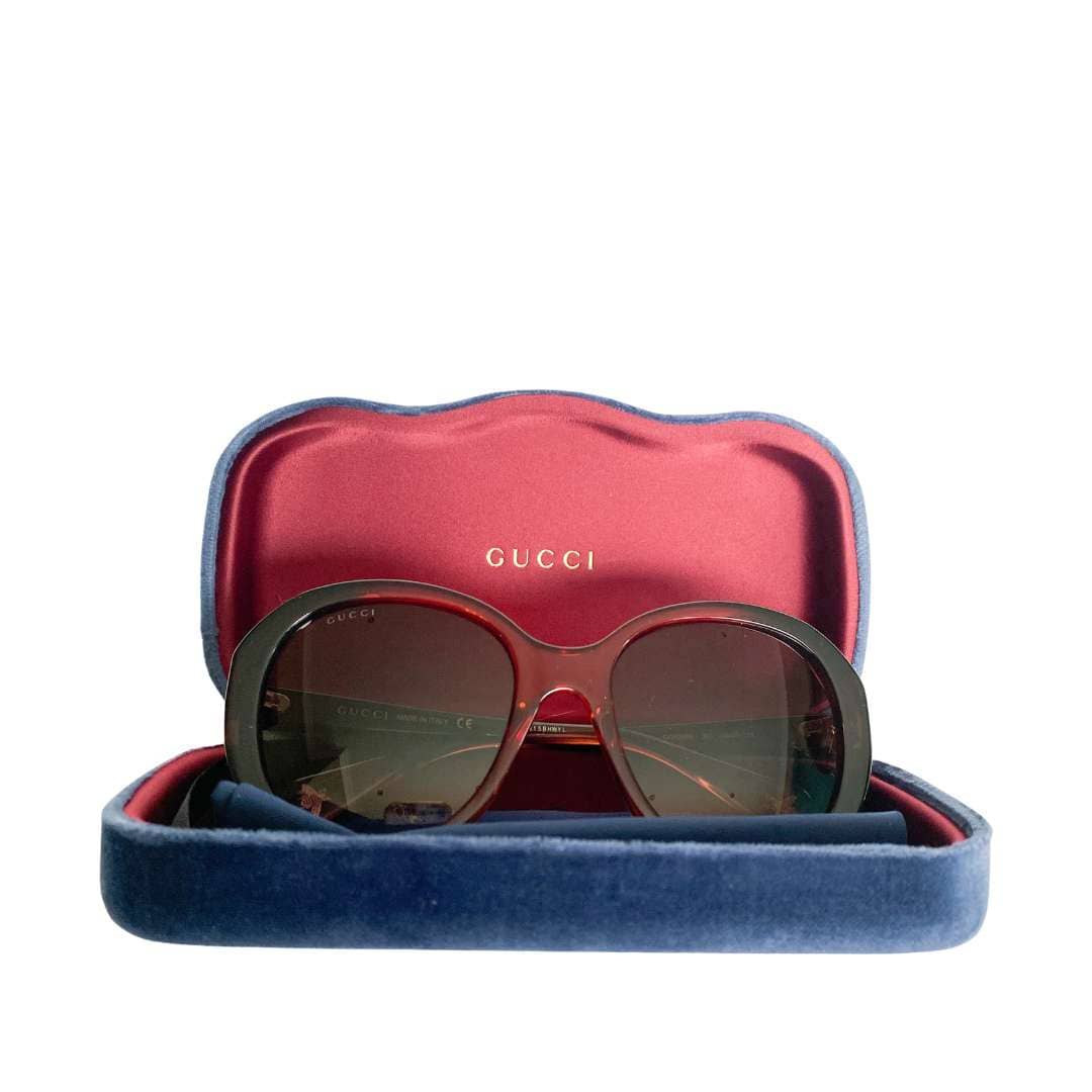 Gucci round sunglasses displayed resting inside their open signature jewel-toned velvet hard case.