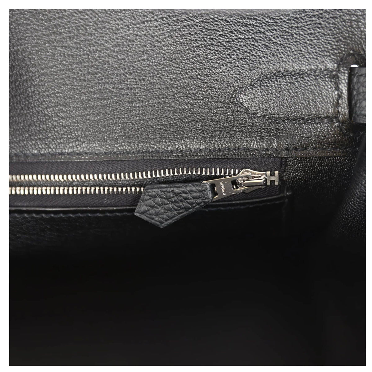 Macro detail view of interior blind stamp and zip pocket inside the black Togo Hermès Birkin 30 bag.