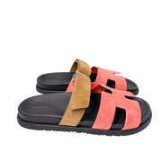 Three-quarter angle of the Rouge Tomette Hermès Chypre slide, showing the adjustable velcro strap wrapped in a textured, earth-toned fabric.