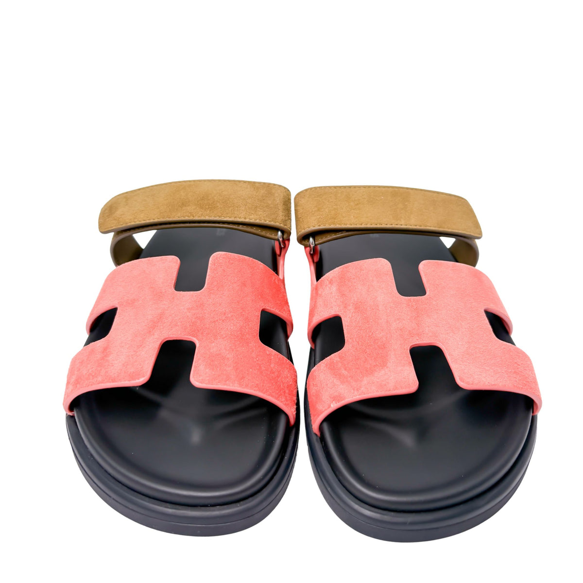 Symmetrical studio shot of both Hermès Chypre sandals side-by-side, highlighting the signature anatomical black calfskin footbeds and open toe design.